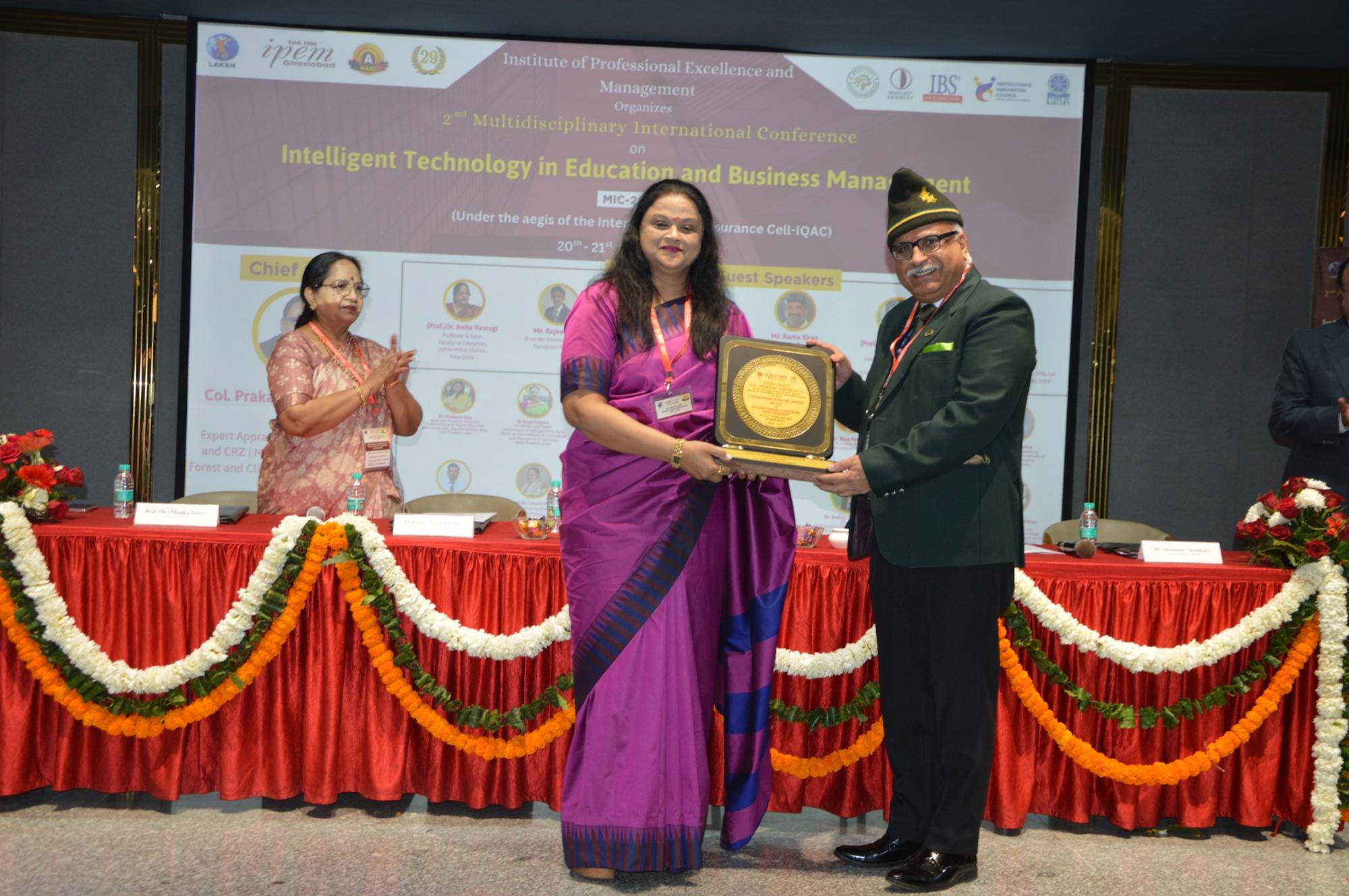 A memento is presented on stage beneath the conference backdrop.